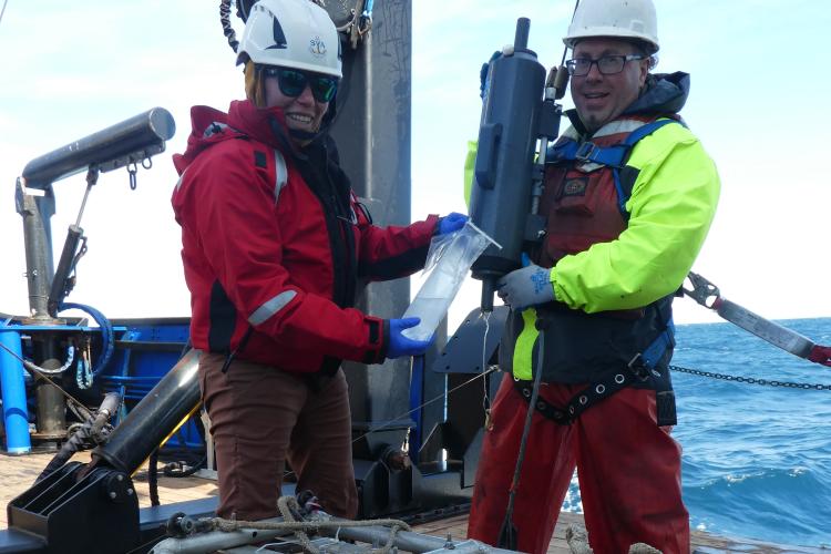 Two scientists extracting eDNA from Niskin bottle water sample.