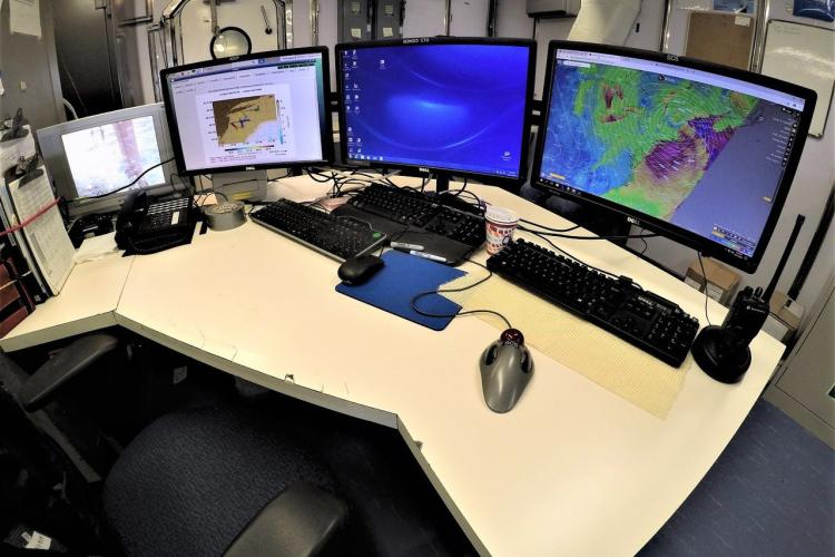 Workstation with 4 monitors, 2 keyboards, radio and walkie talkie. 