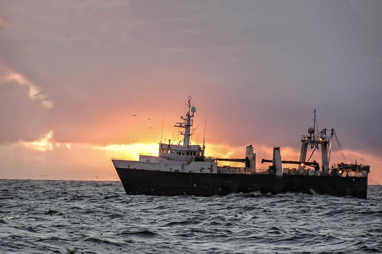 Ship at sea with sunset behind it 