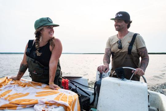 A woman smiling at her brother as he drives a boat.