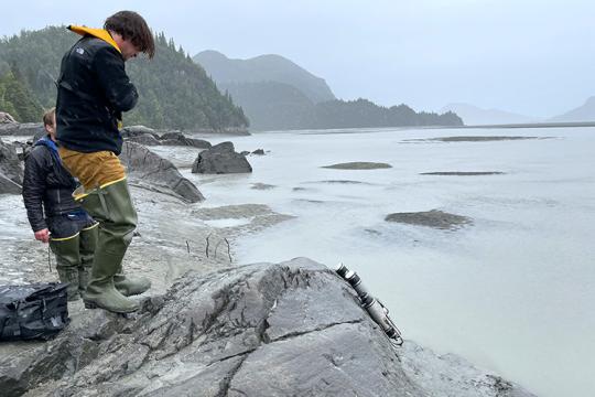 Scientist looking at scientific equipment near a lake with hills and trees