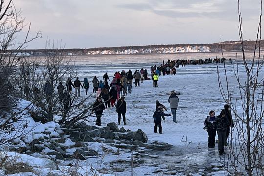 A crowd of people surrounds a fin whale carcass on the shore
