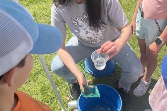 Veronica Runge dips an individual recently PIT-tagged fish so each student can release them into the Columbia River. Credit Ben Sandford, NOAA Fisheries 