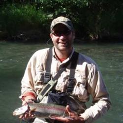 Nathan Keith, holding fish while standing in stream.