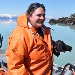 Woman holding a camera with mountains in background