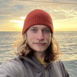 Landon Flake in hoodie and orange hat by the water.