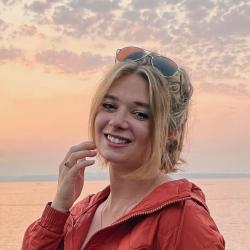 Paige Hanson in oranage jacket at the beach at sunset.