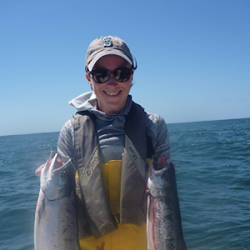 Women in boat, holding 2 fish.