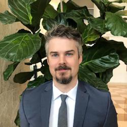 Robert Murphy with beard in front of potted plant. 