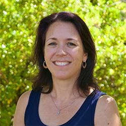Portrait of a scientist with brunette hair with green bushes in background