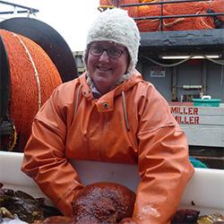 Scientist wearing orange jumpsuit, hat and glass holding an octopus.