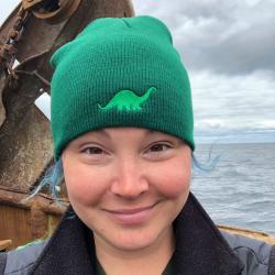 Maura Flynn in green dino hat onboard fishing vessel. 