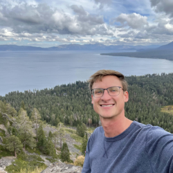 Portrait of Robert McLean on a mountain with water in the background. 