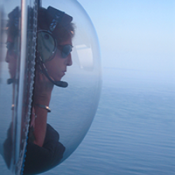 Woman looking out of convex window at sea