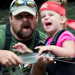 Josh Keaton with a child, fishing rod, and fish
