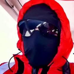 Man wearing black face mask and an orange coat with a hood