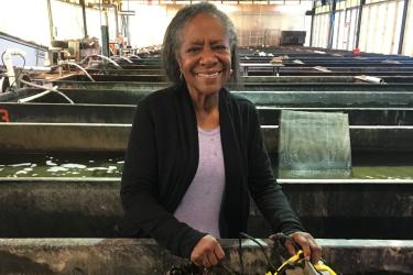 Sheila Stiles stands in the Milford Lab tank farm, holding a bag of mussels