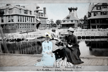 Four women, including Mary Jane Rathbun, sitting on a Fish Commission wharf dock in Woods Hole, Massachusetts. 