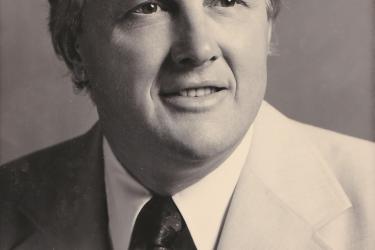 black and white portrait of a smiling man wearing a suit and tie