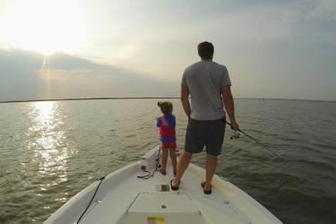 Man and child fishing off boat