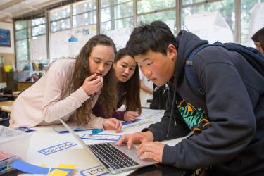 Students working together around a laptop computer