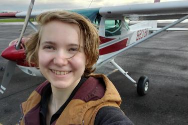 Headshot of Abi in front of a red and white Cessna 152.
