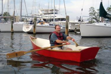 a man in a red boat rows in a small harbor. 