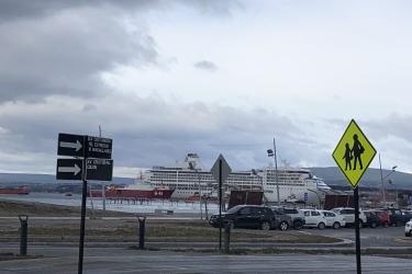 large cruise ship off in distance. Parking lot in fore front.