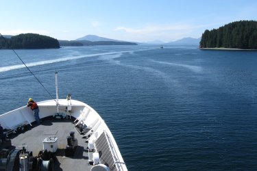 Man at the bow of the NOAA Ship Rainier as it departs Kodiak, Alaska