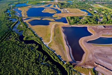 Aerial view of a wetland preserve with ponds, trails, and mangroves