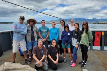 Eleven scientists standing in a group on the back deck of a ship.