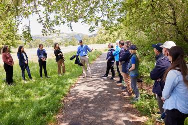 Chris Wood speaking to a group of people gathered along a wilderness trail