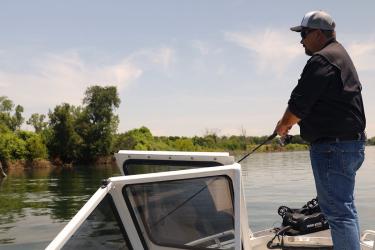 Man aboard a boat casting a fishing line