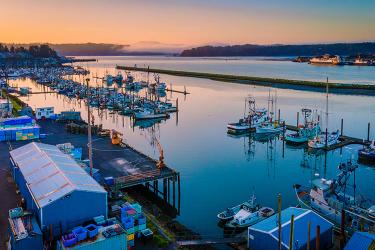 Many docked fishing boats at a coastal community at sunrise.