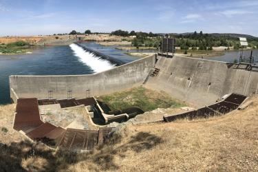 Dam and concrete fish ladder in a dry, gold, California landscape