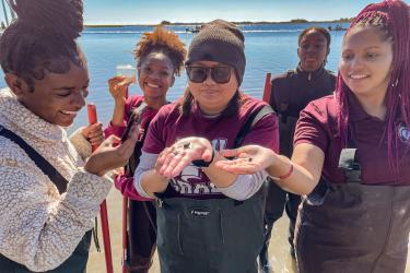 Lauren Johnson, far right, and other students show off marine life they found on an NCCU field visit. (Credit: North Carolina Coastal Federation)