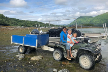 Father and daughter sitting on an ATV at an oyster farm in Alaska