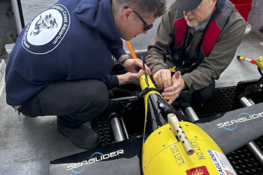 Photograph of two scientists on a small boat preparing glider for deployment.
