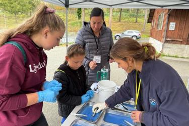 Tribal members wearing gloves at a table engaging in an activity.