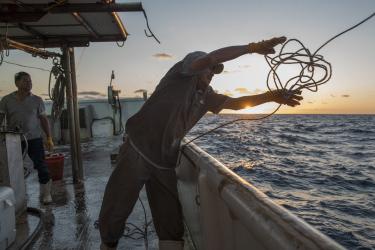 A man throw a rop off the side of a boat 