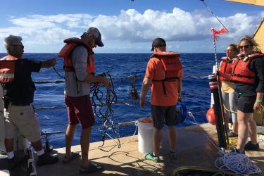 A group of scientists ready gear on the deck of a ship. 