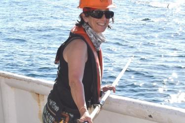 Lisa Natanson in hard hat and safety gear with shark tagging pole. 