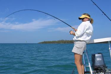 Fishing in the Gulf of Mexico, women on the stern of a boat in shorts and visor. 