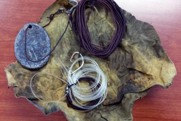 Fishing lines and weight coiled up on a square of fabric. 