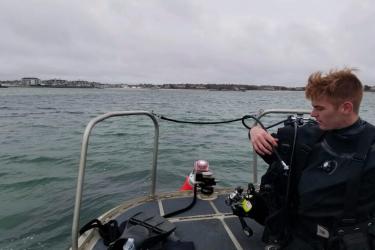 Alex Creed checking dive gear in bow of boat.