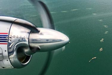 Propeller of a aerial survey plane in the foreground with ocean beneath