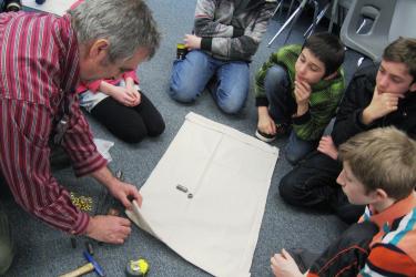 Adult surrounded by young students showing how to build a drifter.
