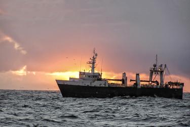 Ship at sea with sunset behind it 