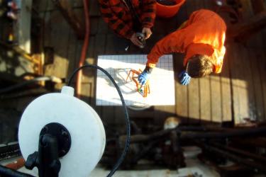 Observer in orange jacket using grid system to electronically measure a crab.