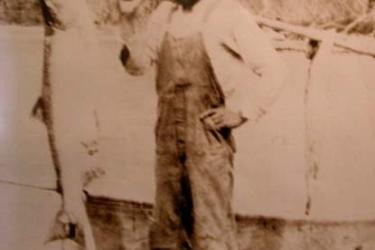 Man carrying a fish on a stick over his shoulder
